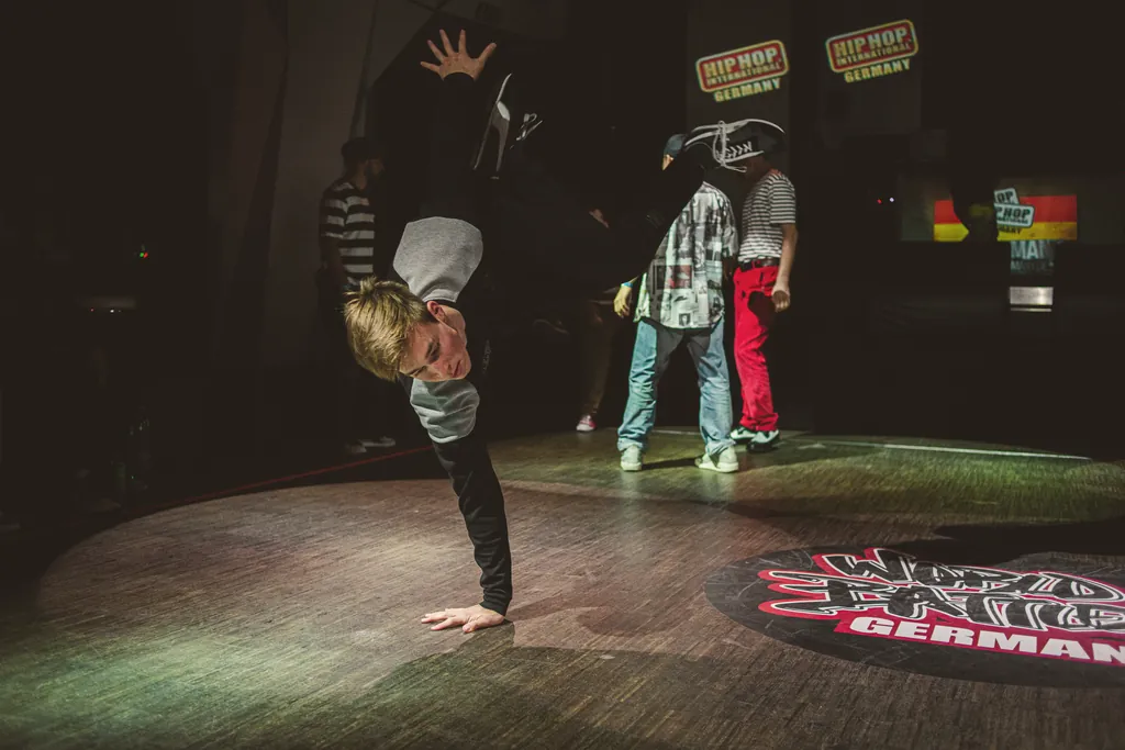Young b-boy balancing on one hand on the World Battles Germany logo