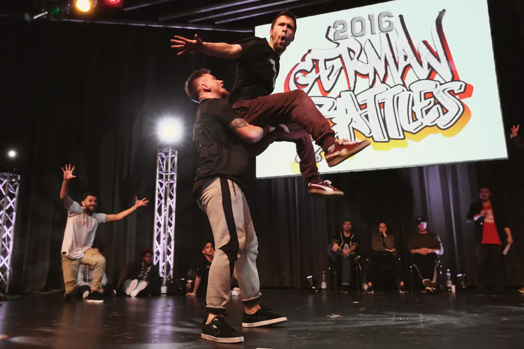 Two dancers at the German Battles 2016: one jumps onto the other’s shoulder while the judges cheer