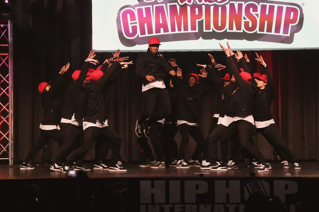 Crew in black with red caps in a wave of arms