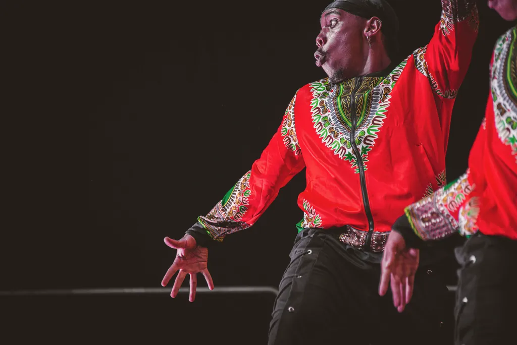 Dancer in a red patterned jacket with an intense expression in the middle of a performance